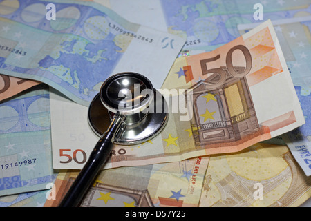 Uno stetoscopio medico appoggiato su molti malati valuta euro Banconote Foto Stock