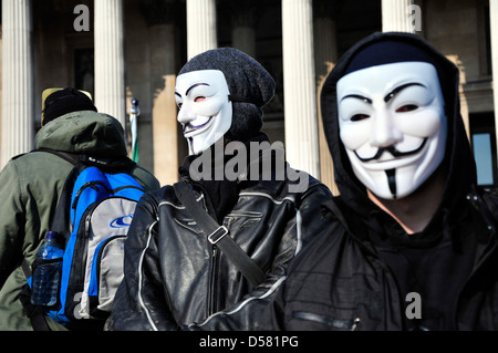 Due manifestanti maschio indossando maschere anonimo in un rally in Trafalgar Square, Londra, Regno Unito. Foto Stock