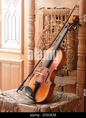Violino giacente su un vecchio e rovinato sedia Foto Stock