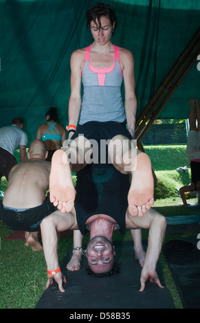 Bali, Indonesia-marzo 20, 2013: le righe di maschio e femmina adulti, giacente su tappeti colorati in una classe di yoga a Bali spirito Festival. Foto Stock