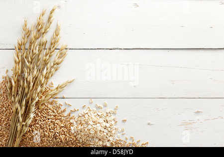 Avena con i suoi elaborati e chicchi grezzi contro il bianco sullo sfondo di legno Foto Stock