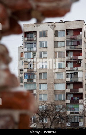 Pernik - una città in Bulgaria: blocco di appartamenti visto attraverso un edificio rovinato Foto Stock