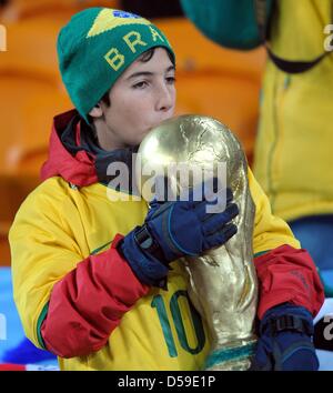 Un bambino con una coppa del mondo trofeo replica nelle gabbie prima della Coppa del Mondo FIFA 2010 Gruppo G match tra Brasile e Costa d Avorio al Soccer City Stadium di Johannesburg, Sud Africa 20 Giugno 2010. Foto: Ronald Wittek dpa - Si prega di fare riferimento a http://dpaq.de/FIFA-WM2010-TC Foto Stock