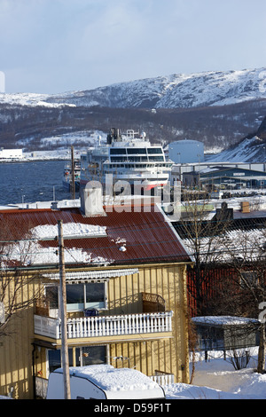 Coperta di neve street di tradizionali case di legno guardando in giù a hurtigruten nave nel porto di kirkenes finnmark Norvegia europa Foto Stock