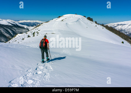 Femmina in rosso con le racchette da neve sul pendio di neve, Plateau de Beille, Pirenei francesi Foto Stock