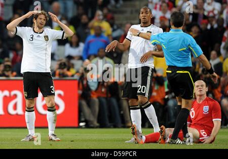 La Germania Arne FRIEDRICH (L) reagisce come compagno di squadra Jerome Boateng guarda, Inghilterra del Wayne Rooney siede sulla terra e arbitro uruguaiano Jorge Larrionda gesti durante la Coppa del Mondo FIFA 2010 Round di sedici match tra Germania e Inghilterra al Free State Stadium di Bloemfontein, Sud Africa 27 Giugno 2010. Foto: Marcus Brandt dpa - Si prega di fare riferimento a http://dpaq.de/FIFA-WM2010 Foto Stock