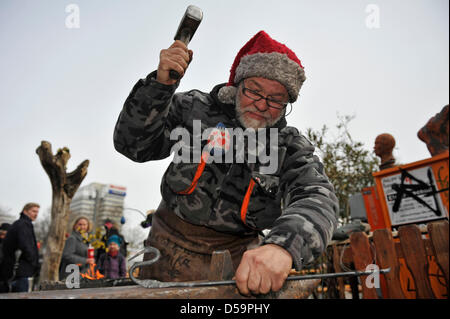 Artigiano Smith Michael Soika forges un pezzo di ferro con un martello al mercato di Pasqua a Alexanderplatz di Berlino, Germania, 27 marzo 2013. Il mercato continuerà fino al 07 aprile 2013. Foto: Markus Heine Foto Stock