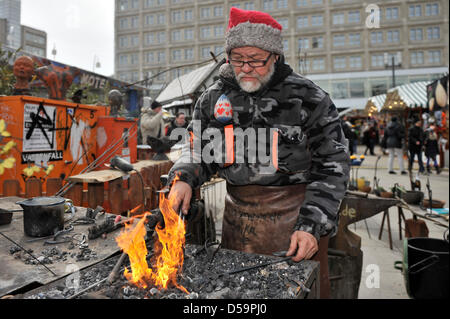 Artigiano Smith Michael Soika riscalda un pezzo di ferro in una fucina presso il mercato di Pasqua a Alexanderplatz di Berlino, Germania, 27 marzo 2013. Il mercato continuerà fino al 07 aprile 2013. Foto: Markus Heine Foto Stock