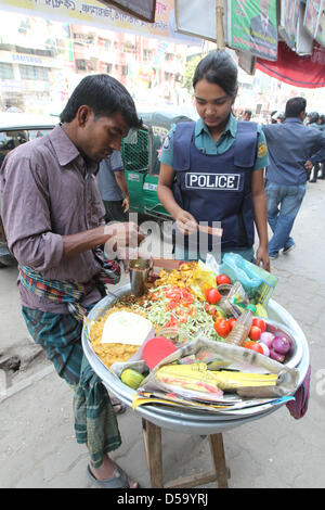 Dacca in Bangladesh. Il 27 marzo 2013. Una donna del Bangladesh polizia acquista un cibo di strada nella parte anteriore del Bangladesh Partito Nazionalista (BNP) partito sede durante uno sciopero nazionale chiamato dall opposizione BNP in segno di protesta contro la detenzione dei loro leader, a Dhaka il 27 marzo 2013. La BNP e i suoi alleati applicate una 36 ore di sciopero generale in tutto il paese principalmente per chiedere il rilascio di più di 150 dei loro leader e attivisti arrestati prima di questo mese. Â©Monirul Alam (immagine di credito: credito: Monirul Alam/ZUMAPRESS.com/Alamy Live News) Foto Stock