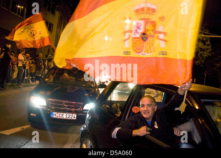 Spagnolo un tifoso di calcio celebra la vittoria su il tedesco della nazionale di calcio durante la Coppa del Mondo FIFA 2010 in Sud Africa da sventola una bandiera spagnola al di fuori di un'auto di pilotaggio a Hannover, Germania, 7 luglio 2010. Foto di Michael Löwa Foto Stock