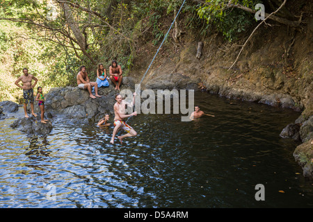 Oscillazione su una corda swing alla cascata di Montezuma, Playa Montezuma, Puntarenas Provincia, Costa Rica. Foto Stock