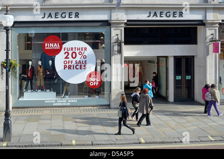 Shopping a piedi sul marciapiede di Regent Street fuori negozio di abbigliamento Jaeger negozio di affari negozio di affari vetrina anteriore vendita poster sconto Londra Inghilterra UK Foto Stock
