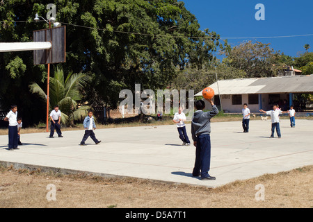 Mexican scolari giocare a palla nel schoolyard durante il recesso. Foto Stock