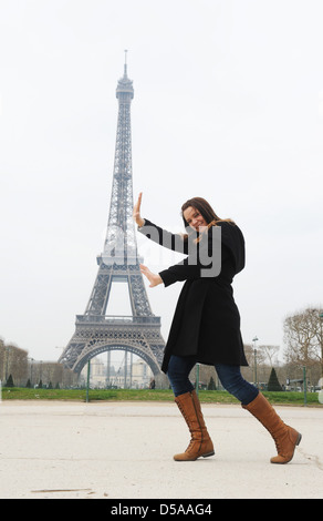 Giovane donna e Torre Eiffel Parigi Francia. Francese punto di riferimento turistico visitatori turismo divertirsi Foto Stock