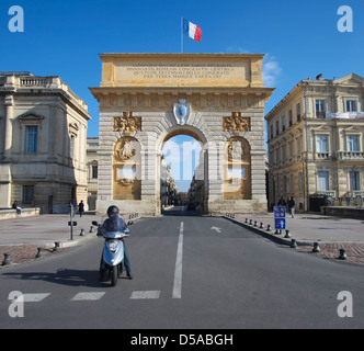 Motociclista e pedoni nella parte anteriore del grand archway a Montpellier, Francia Foto Stock