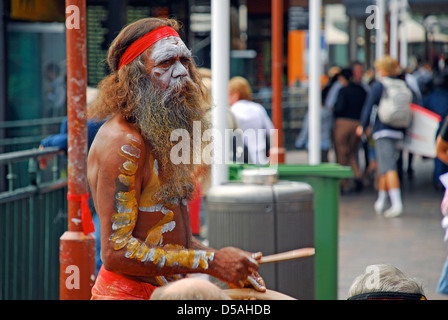 Un aborigeno australiano uomo suona uno strumento musicale per i turisti di fronte a Sydney Circular Quay Ferry Terminal. Foto Stock