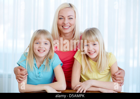 Ritratto di una bella madre che abbraccia il suo figlie gemelle Foto Stock