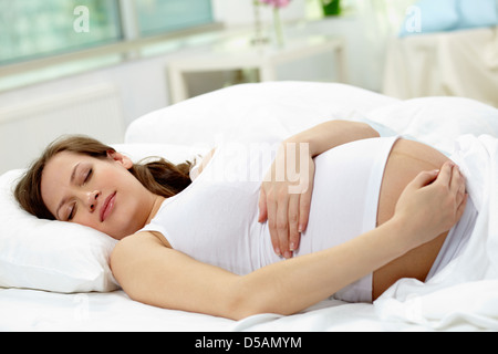 Incinta giovane donna che dorme tranquillamente nel letto Foto Stock