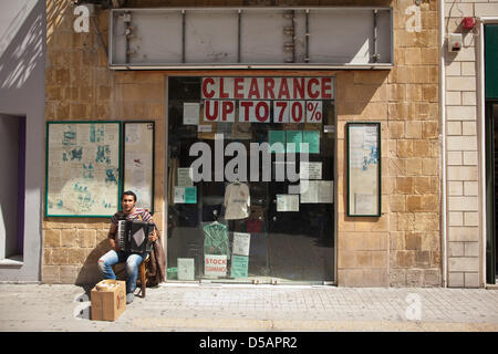 Nicosia, Cipro. Il 28 marzo 2013. La figura mostra un uomo cipriota musicista di strada al di fuori di un negozio la cancellazione è stock a fondere dell'economia in Cyrprus.L'economia cipriota è prevista in diminuzione di circa il dieci per cento. I mercati di tutto il mondo hanno anche reagito male come l'UE segretario finanziario recentemente lodato l'assunzione dei depositanti il risparmio energetico come un modello per la strutturazione in futuro bailouts. Credito: Jeff Gilbert / Alamy Live News Foto Stock