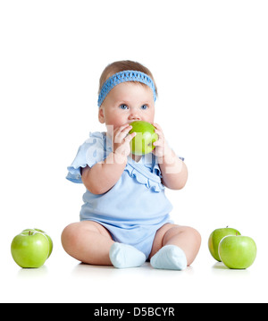 Adorable kid seduto tra i frutti freschi e mangiare mela verde. Foto Stock