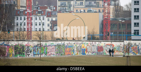 I passanti per visualizzare il lato posteriore della East Side Gallery di Berlino, Germania, 28 marzo 2013. Quattro elementi di parete sono stati rimossi per rendere possibile un accesso a un sito in costruzione. Un investitore piani per la costruzione di un alto edificio di appartamenti sul grafico a destra accanto al fiume Sprea. Foto: SOEREN STACHE Foto Stock