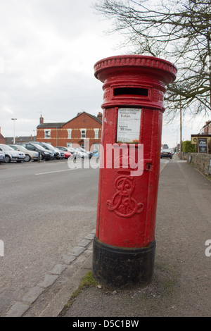 Red royal mail postbox sul lato di una strada Foto Stock