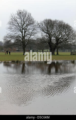 Il Parco di Richmond, Inghilterra, Regno Unito. 28 marzo, 2013. Walkers sfidare il freddo il Giovedì Santo vicino al laghetto che si è formato nel caso in cui la pioggia infinita ha allagato campi nei pressi Roehampton cancello in Richmond Park. Il più grande dei parchi reali, è una riserva naturale nazionale, London il più grande sito di particolare interesse scientifico e un europeo zona speciale di conservazione. Foto Stock