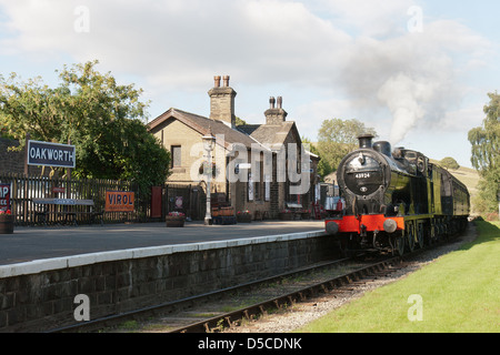 Locomotiva a vapore la trazione di un treno passeggeri sulla Keighley e vale la pena di ferrovia a Oakworth, nello Yorkshire, Inghilterra Foto Stock