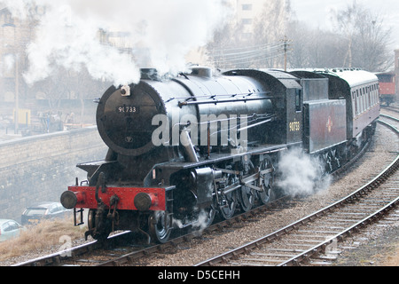 Locomotiva a vapore la trazione di un treno passeggeri sulla Keighley e vale la pena di valle ferroviaria a Keighley, West Yorkshire, Inghilterra Foto Stock
