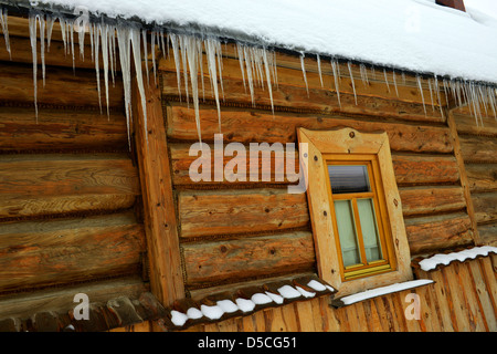 Ghiaccioli e coperta di neve case di legno nel pittoresco villaggio di Chocholow nei monti Tatra vicino a Zakopane in Polonia. Foto Stock