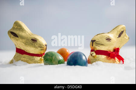 Illustrazione - un'immagine illustrata mostra due cioccolato conigli pasquali e colorate uova di Pasqua in piedi nella neve a Olympiapark in Monaco di Baviera, Germania, 29 marzo 2013. Foto: MARC MUELLER Foto Stock