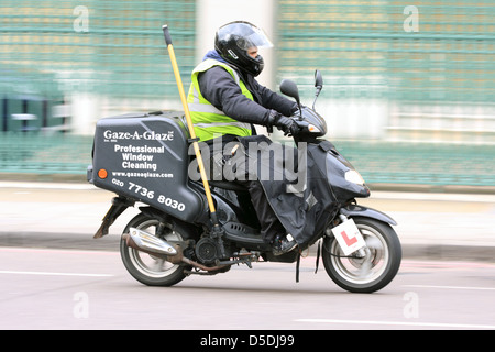 Un motociclista in sella lungo una strada nei pressi di Waterloo a Londra in Inghilterra. con la pubblicità sul retro della sua moto Foto Stock