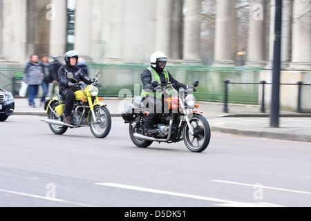 Due motociclisti in sella vecchia moto lungo una strada a Londra, Inghilterra. Foto Stock