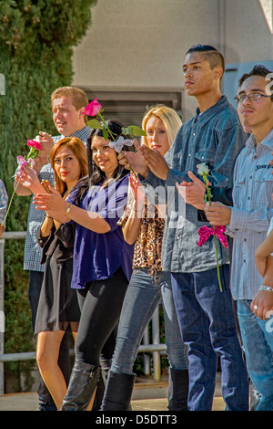 Azienda rose come regali per la laurea, casualmente vestito studenti allietare i compagni di scuola sul giorno di graduazione in continuazione di alta scuola. Foto Stock