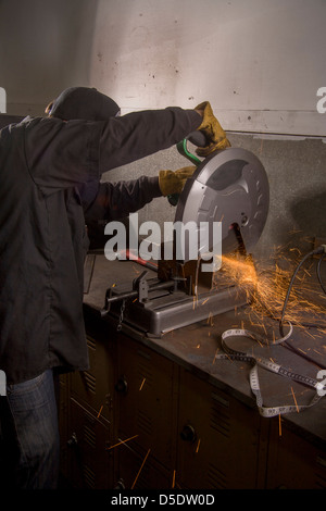 Le scintille volano come uno studente di scuola superiore utilizza una sega circolare per tagliare un tubo di metallo in negozio di auto di classe a San Clemente, CA. Foto Stock