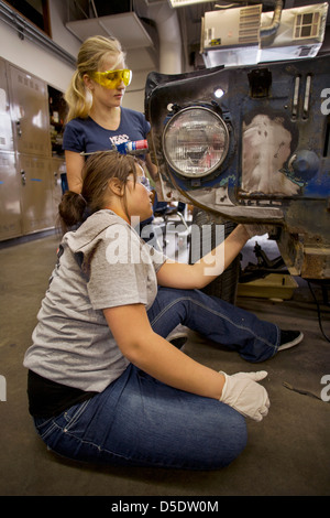 Indossare occhiali di sicurezza due ragazze adolescenti a lavorare insieme su un auto in auto shop classe in San Clemente, CA. Foto Stock