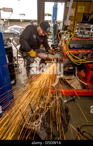 La formazione di scintille volare come un ragazzo adolescente di grind un metallo raccordo di motore nel negozio di auto di classe a San Clemente, CA. Foto Stock