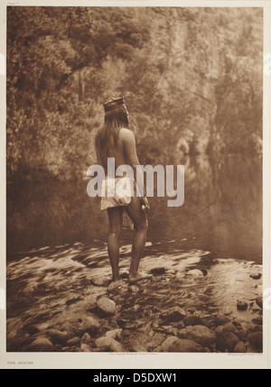 Un ritratto di un uomo nativo Apache americano, catturato da Edward S. Curtis. La fotografia dei primi anni del XX secolo presenta abiti Apache tradizionali e fornisce uno sguardo sulla vita delle tribù native americane lungo il fiume. Foto Stock