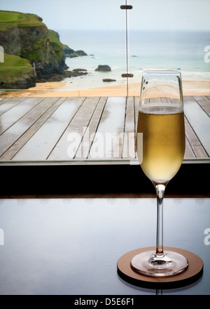 Bicchiere di champagne in un resort si affaccia sul litorale della Cornovaglia, la spiaggia e la scogliera Foto Stock