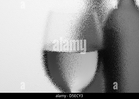 Le bottiglie di vino e Wineglass visto in monotono attraverso una finestra testurizzata con retroilluminazione. Composizione orizzontale con copyspace. Foto Stock