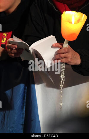 Il 29 marzo 2013, Colosseo Quadrato, Roma: un pellegrino è la lettura del libretto di preghiere con un Rosario nelle sue mani, durante la Via Crucis presieduta dal Papa Francesco I intorno al Colosseo il Venerdì Santo. Foto Stock