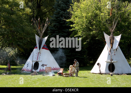 Un Native American Indian tende Tepee campeggio con gli uomini che giocano il tamburo e flauto Foto Stock