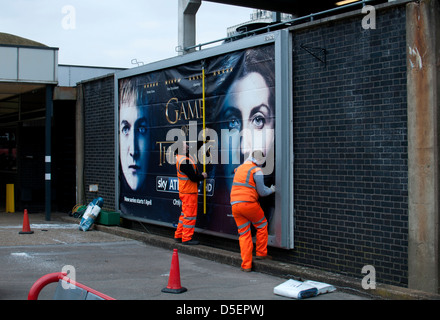 Gli uomini mettendo su affissioni poster, stazione di Coventry, Regno Unito Foto Stock