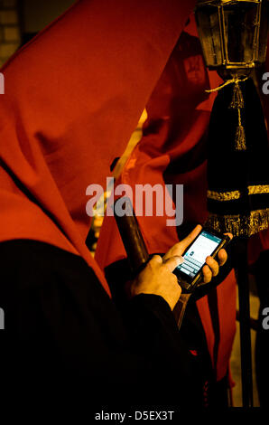 Barcellona, Spagna. 29 marzo, 2013. Nazareno della "Nostra Signora dei Dolori" fratellanza nel suo costume medievale utilizzando high tech. - La Fraternità di "Nuestra Señora de las Angustias' (la Madonna Addolorata) è uno dei tre confraternite organizzando e partecipando alla processione del Venerdì santo attraverso il centro gotico di Barcellona seguita da migliaia di cittadini e turisti. Foto Stock