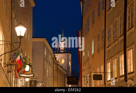 Una vista lungo Getreidegasse al municipio della città vecchia torre dell orologio al crepuscolo in Altstadt, Salisburgo, Austria Foto Stock
