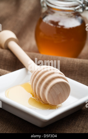 Miele liquido in piccolo vasetto di vetro, il fuoco selettivo Foto Stock