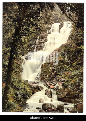 Una fotografia panoramica della Torc Cascade, una cascata situata nella contea di Kerry, Irlanda. L'immagine mostra la bellezza naturale dell'acqua a cascata circondata dal verde lussureggiante di Killarney. Foto Stock