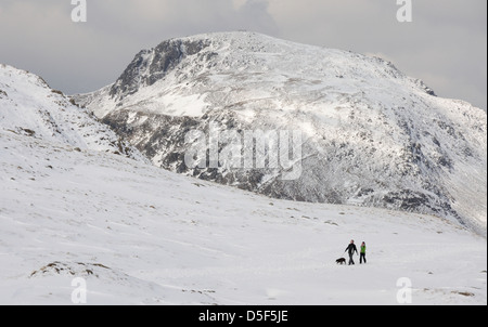 Walkers accanto agli spruzzi Tarn in inverno nel Lake District inglese, con grande timpano in background Foto Stock