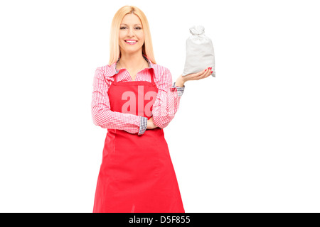 Un sorridente casalinga indossando grembiuli e tenendo una sacca isolata contro uno sfondo bianco Foto Stock