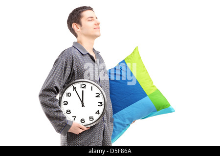 Un giovane uomo con cuscino e orologio sonnambulismo isolati su sfondo bianco Foto Stock